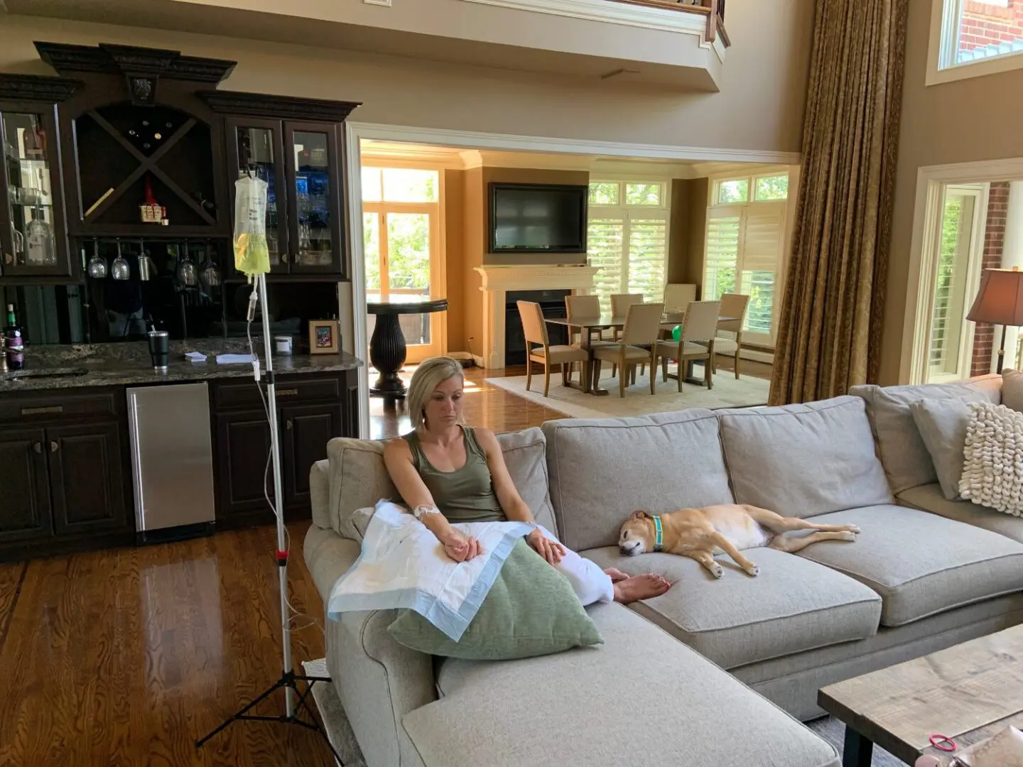 A woman sitting on top of a couch next to a dog.