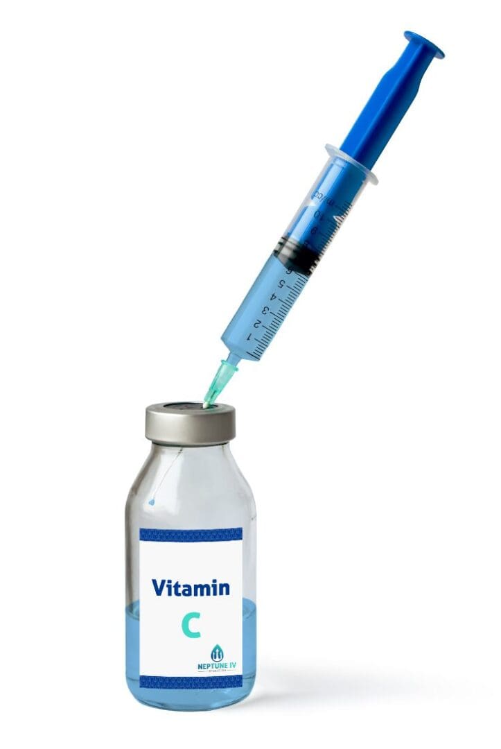 A syringe drawing a bright blue liquid from a bottle labeled "vitamin C" for IV hydration therapy.