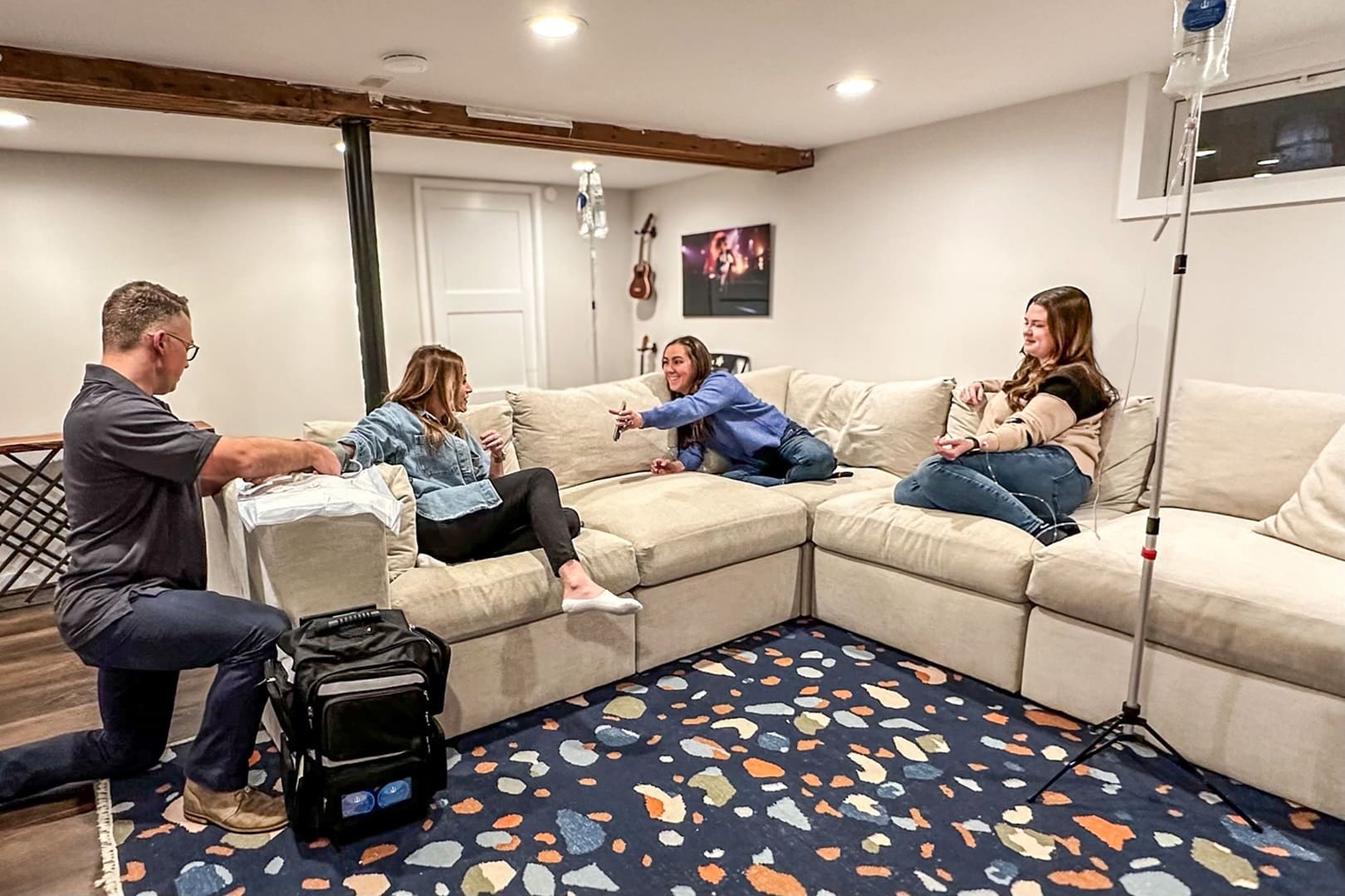 Group of friends enjoying a casual conversation in a cozy living room with a comfortable sofa and considering mobile iv therapy for vitamins.